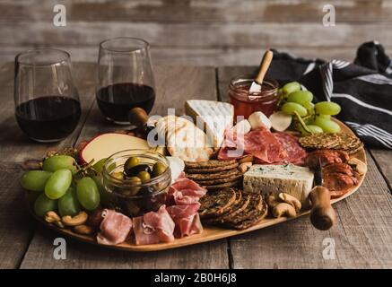 Nahaufnahme von Charcuterie-Tafel und Gläsern Wein auf Holztisch. Stockfoto