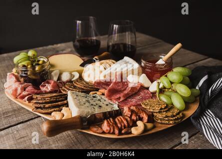 Nahaufnahme von Charcuterie-Tafel und Gläsern Wein auf Holztisch. Stockfoto