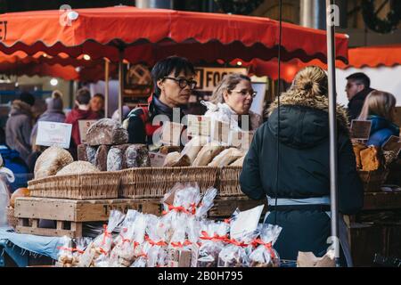 London, Großbritannien - 29. November 2019: Verkäufer auf dem Brot- und Konditorstand im Borough Market, einem der größten und ältesten Lebensmittelmärkte Londons, interagieren Stockfoto