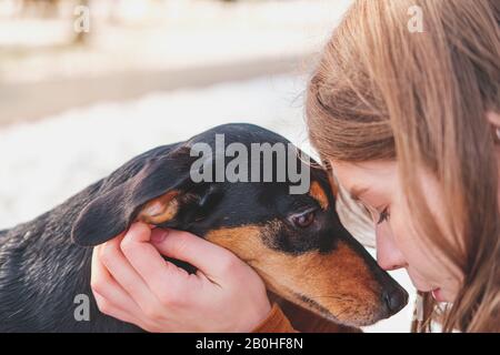 Liebende und ehrende Hunde: Frau mit ihrem Welpen. Junge Frauen und Dachshund kleben und umarmen bei einem Spaziergang im Freien Stockfoto