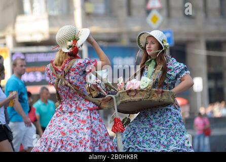 Mädchen Straßenhändler in hellen Vintage-Kleidern, die Tabletts mit Süßigkeiten halten und kommunizieren. April 2019. Kiew, Ukraine Stockfoto