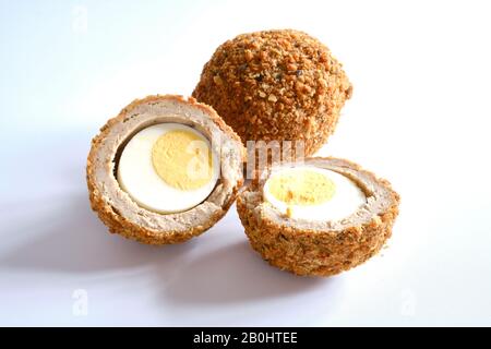 Scotch Eggs ein traditioneller herzhafter Snack, bestehend aus einem hart gekochten Ei, umgeben von Wurstfleisch und Brot-Krümel-weißem Hintergrund Stockfoto