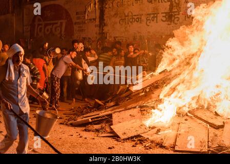 Die Menschen, die Kohle ausziehen, bezeichnen die sagenhafte Figur des Prahlad aus dem traditionellen Holika-Dahan-Feuer auf das Hindufest von Holi. Vrindavan. Indien Stockfoto