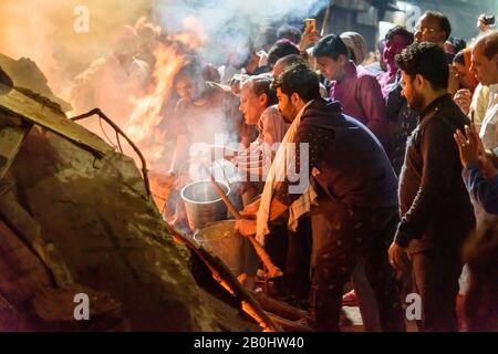 Die Menschen, die Kohle ausziehen, bezeichnen die sagenhafte Figur des Prahlad aus dem traditionellen Holika-Dahan-Feuer auf das Hindufest von Holi. Vrindavan. Indien Stockfoto