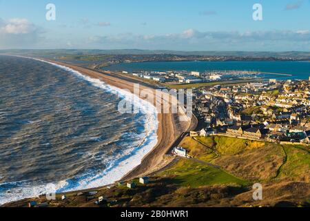 Fortuneswell, Portland, Dorset, Großbritannien. Februar 2020. Wetter in Großbritannien. Blick von der Spitze der Klippen von West Weares über Fortuneswell auf der Insel Portland in Dorset während der späten Nachmittagssonne mit bösen Winden und rauem Meer, das am Chesil Beach in Chiswell an Land stürzt. Bildnachweis: Graham Hunt/Alamy Live News Stockfoto
