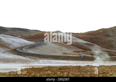 Auto auf der kurvenreichen windigen Landstraße nach leichtem Schnee, Nordisland Stockfoto