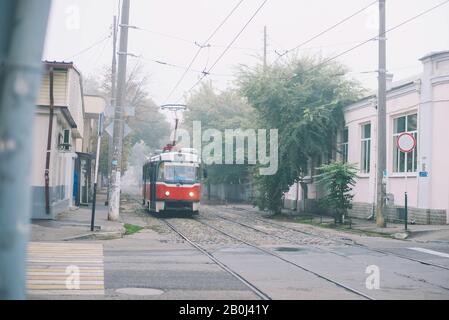 Historische rote Straßenbahn im Nebel auf der Straße in der Einlage Stockfoto