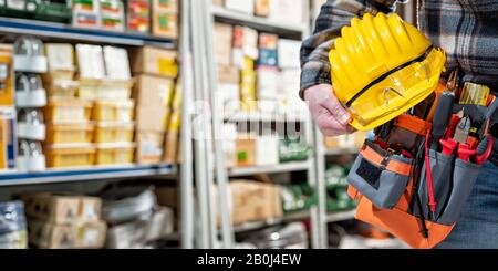 Der Elektriker im Elektrofachgeschäft hält Helm und Schutzbrille in der Hand. Bauindustrie, Elektrik. Stockfoto