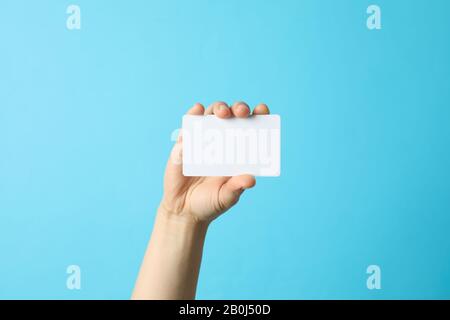 Weibliche Hand hält leere Visitenkarte auf blauem Hintergrund Stockfoto