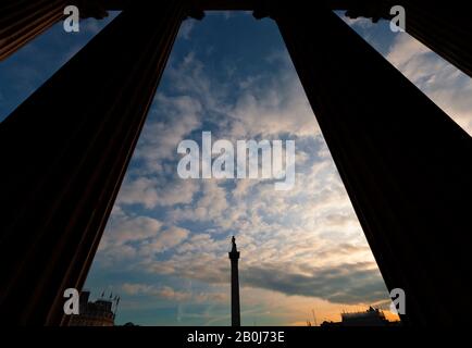 Die Nelsonsäule betrachtet durch die Säulen am Eingang in die National Gallery Stockfoto