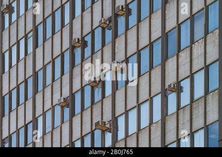 Externe Klimaanlagen hängen an der Fassade eines alten Gebäudes aus dem Jahr 1964 Stockfoto