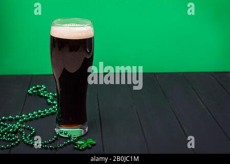 Glas dunkles Bier und traditionelles Kleeblattdekor Stockfoto