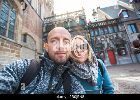 Ein junges Touristenpaar vor dem Hintergrund der Basilika vom Heiligen Blut auf dem Burgplatz in Brügges, Belgien. Stockfoto