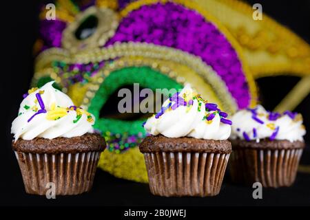 Drei kleine Cupcakes auf schwarzem Hintergrund mit verschwommener Maske. Geringe Schärfentiefe. Stockfoto