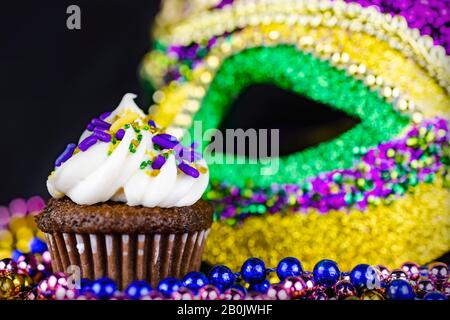 Nahaufnahme eines kleinen Cupcakes mit farbiger Maske, die im Hintergrund verschwommen ist. Stockfoto