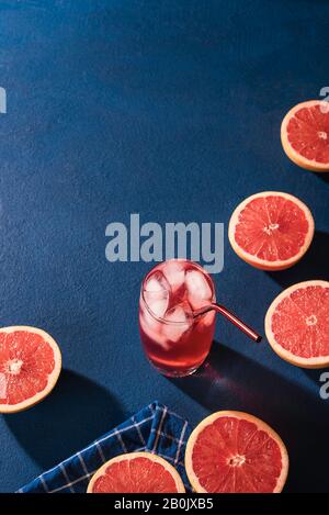 Reife Grapefruits, halbiert und Glas Grapefruit Limonade mit Eiswürfeln. Kaltes Sommergetränk. Frische tropische Früchte.Grapefruit Getränk. Stockfoto