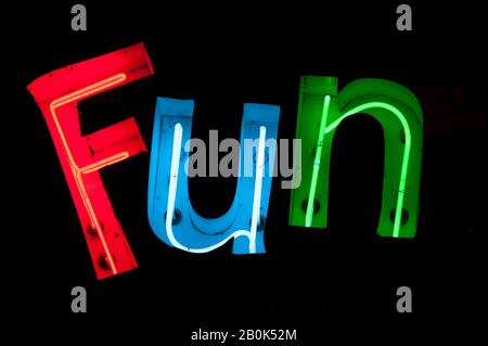 Das Wort Fun hat in bunten Neon-Schriftzügen auf schwarzem Hintergrund aufgeschrieben Stockfoto