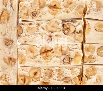 Italienische festliche Torrone (oder Nougat) mit Haselnüssen auf weißem Hintergrund. Stockfoto