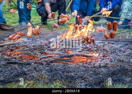 Grillen von Würstchen im offenen Feuer mit großen Familientreffen Stockfoto