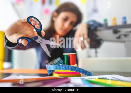 Schneidegeräte messen Band, Schere und Gewinde und Nadel in der Werkstatt. Geringe Schärfentiefe auf dem Modedesigner-Symbol. Modekonzept. Stockfoto