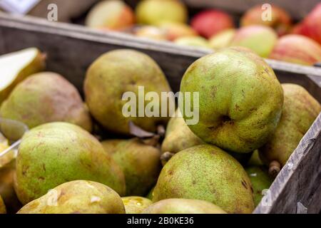 Ein Porträt einer Holzkiste voller Birnen auf einem lokalen Markt. Im Hintergrund befinden sich verschwommene Appel auch in einer Holzkiste. Die Frucht ist bereit Stockfoto