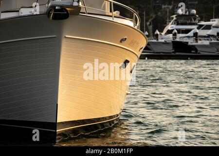 Motoryacht-Schleife im Wasser auf der linken Seite des Bildes, das bei Sonnenuntergang vorne gesehen wird Stockfoto