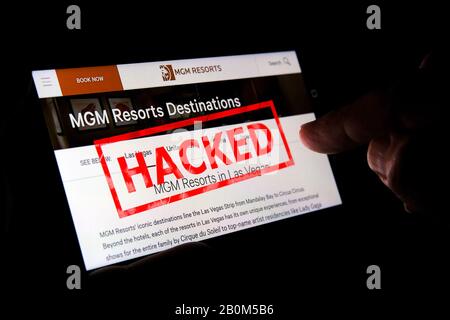 MGM-Website auf dem Smartphone-Bildschirm mit einem roten Stempel, DER OBEN GEHACKT ist und mit dem Finger darauf zeigt. Konzept. Redaktionelle Illustration. Stockfoto