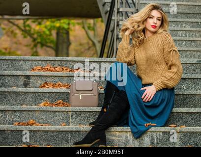 Trendy fühlen. Herbstfrau lockiges Haar im Freien. Legere Style-Studentin. Herbstsaison. Weibliche Schönheit. Modelart: Mädchen in Wellrock und Pullover. Plissierter Trend: Mädchen lange blonde Haartreppen. Stockfoto