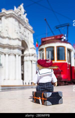 Der kleine Reisende Teddybär trägt Matrosenanzug und Beret Hut, sitzt auf seinem Koffer und wartet auf die Straßenbahn in Lissabon (Copy-Space) Stockfoto