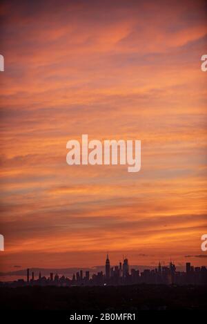 Ein schöner Sonnenuntergang über der Skyline von Manhattan wird von einem Fenster in Kew Gardens, Queens, aus gesehen. Stockfoto