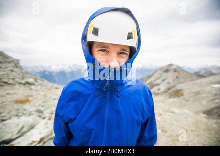 Porträt des Bergsteigers mit Helm und Regenjacke. Stockfoto