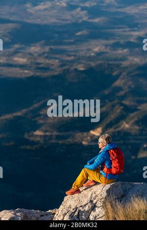 Junge Frau auf Felsen auf einem Berg mit Blick über. Stockfoto