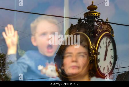 Bukarest, Rumänien - 28. Oktober 2018: Mutter und Sohn blicken auf das Fenster einer alten rumänischen V56-Straßenbahn an einer eisernen Uhr an einer Straßenbahnparade i Stockfoto