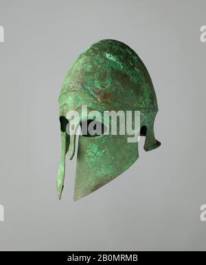 Helm des korinthischen Typs und Paar Greaves, Griechisch, Anfang 5. Jahrhundert v. Chr., Griechisch, Bronze, Helm: H. 12 1/16 Zoll (30,6 cm); W. 7 1/4 Zoll (18,5 cm); D. 10 13 / 16 Zoll (27,4 cm); Wt. 2 lb. 0,85 oz. (931 g); rechtes Schmierfett: H. 15 3/8 Zoll (39,1 cm); W. 4 15/16 Zoll (12,5 cm); D. 6 3/8 Zoll (16,2 cm); Wt. 1 lb. 2,5 oz. (525 g); linke Schmierfalle: H. 15 7/16 Zoll (39,2 cm); W. 5 1/4 Zoll (13,3 cm); D. 6 1/16 Zoll (15,4 cm); Wt. 1 lb. 1,4 oz. (492 g), Armor Parts Stockfoto