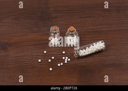 Homöopathische Globules und drei Glasflaschen auf Holzhintergrund Stockfoto