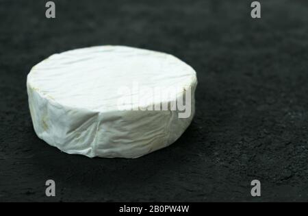 Ein ganzer Kopf von Camembert-Käse auf schwarzem Hintergrund. Kopierbereich. Stockfoto