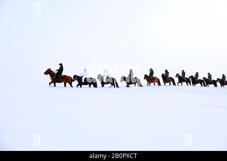 Chinesische Polizisten, Grenzsoldaten und medizinische Arbeiter fahren Pferde im Schnee, um lokale Familien zur Prävention des neuen Coronavirus und p zu besuchen Stockfoto