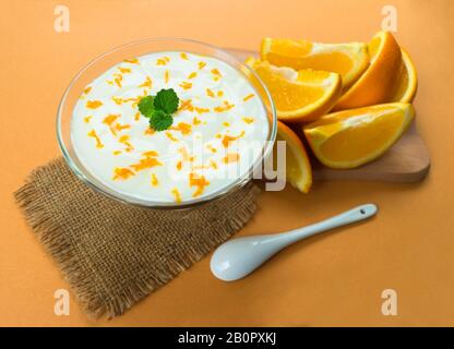 Leckerer Joghurt mit orangefarbenem Smoothie auf orangefarbenem Hintergrund. Draufsicht. Stockfoto