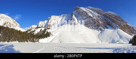 Weite Panorama-Winterlandschaft von Zerklüfteten Bergspitzen über Dem Gefrorenen Schnee Bedeckt Chester Lake, Kananaskis Country Rocky Mountains Alberta Kanada Stockfoto