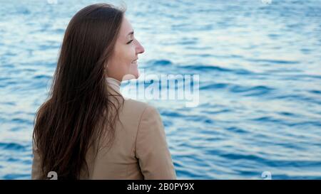 Junge Dame mit dunkellangem Haar genießt eine fantastische, seekape Position am gegenüberliegenden Ufer auf der Rückansicht des Urlaubs Stockfoto