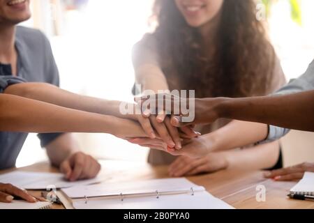 Nahlächelnde, verschiedene Studenten oder Mitarbeitergruppen, die die Hände beim Treffen zusammenbringen, Unterstützung und Einheit zeigen, das Business-Team, das sich mit Teambuild beschäftigt Stockfoto