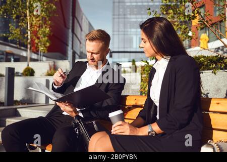 Business Leute lesen Dokumente unterschreiben sitzen auf einer Straße der Stadt. Stockfoto