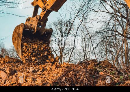 Kulisse des Baggereimer mit Erde auf Wald- und Himmelshintergrund. Stockfoto