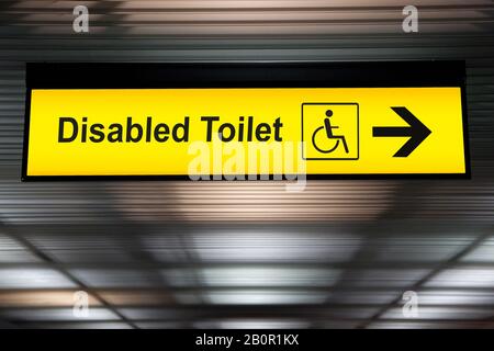 Schild mit Pfeilspitze zur behindertengerechten toilette am Flughafen für Passagiere mit Körperbehinderung. Universelles Design für Senioren oder Behinderte im öffentlichen Raum Stockfoto