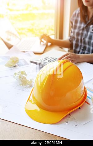 Architektin Asian Woman arbeitet mit Laptop, Taschenrechner und Blaupausen. Ingenieur berechnet und überprüft am Arbeitsplatz die Baupläne Stockfoto