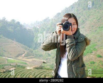 Asiatische Touristin Backpacker fotografieren in der Natur auf den Bergen, Chiang Mai, Thailand im Urlaub, Teeplantage im Hintergrund Stockfoto