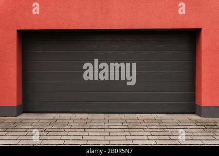 Moderne Garage mit grauer Tür und roter Wand Stockfoto