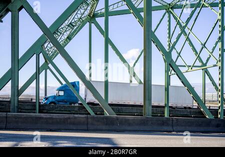 Großer, leistungsstarker industrieller Langstrecken-blauer Diesel-Sattelschlepper mit Grillschutz, der kommerzielle Fracht im trockenen Kleintransporter transportiert, der auf dem Tr fährt Stockfoto