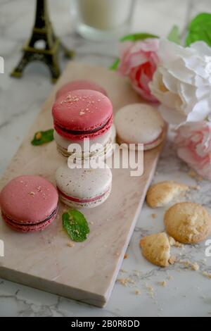 3/4-Schuss Farbenfroher Pastellmakarone auf Marmortablett mit Keksen und Dekorationen auf Marmorschreibtisch Stockfoto