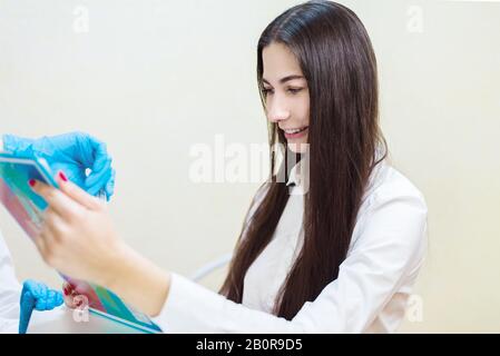 Junges Mädchen lächelt an der Arztaufnahme, der Patient füllt einen Fragebogen in der Klinik aus Stockfoto